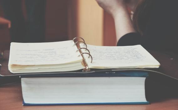Open spiral bound book on top of a closed book