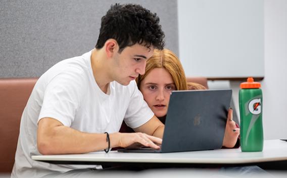 Students looking intently at a shared laptop