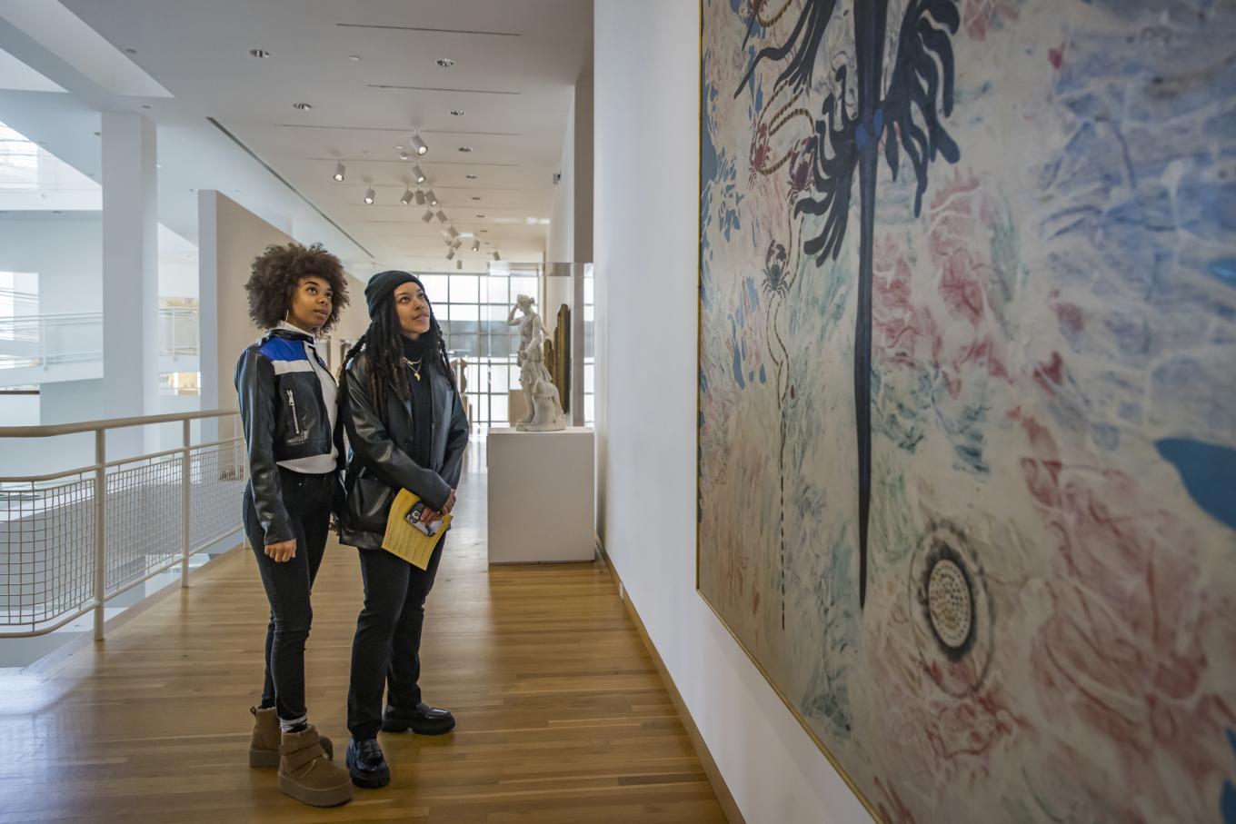 Museum patrons looking up a large painting