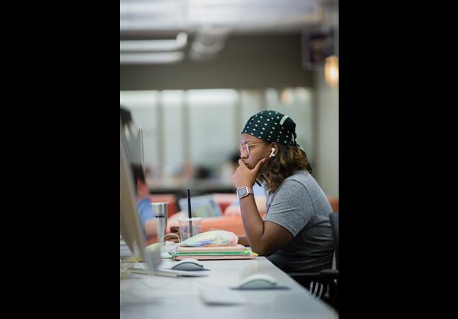 Student at a desktop computer station, listening to earbuds