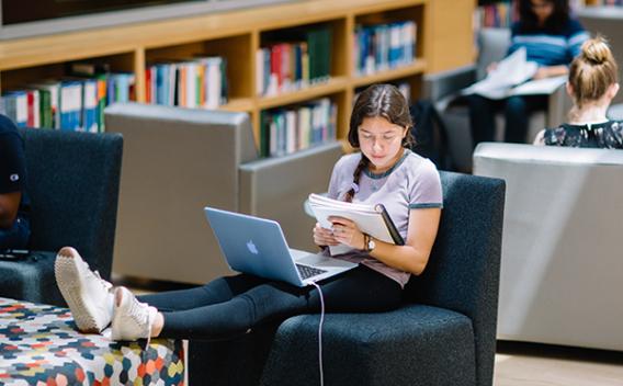 Student with feet up on ottoman bench in the Atwood Science Commons