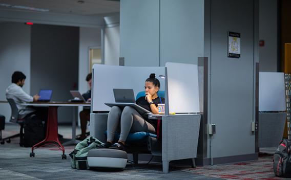 A female student working on her laptop in a cubby on the first floor of the Woodruff Library